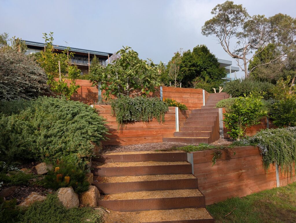 Sleeper retaining walls with rusty corten steel steps in McCrae.